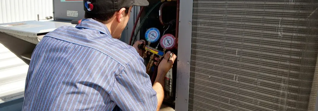 HVAC technician servicing a condenser unit in Morgantown